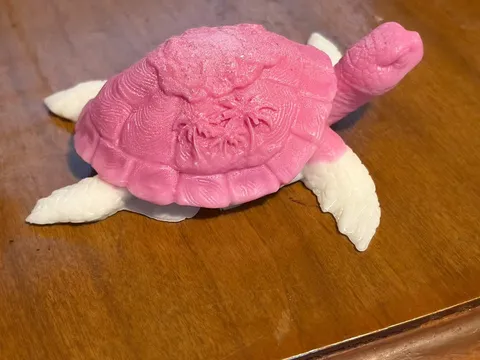 Pink and white turtle shaped soap on a wooden table.